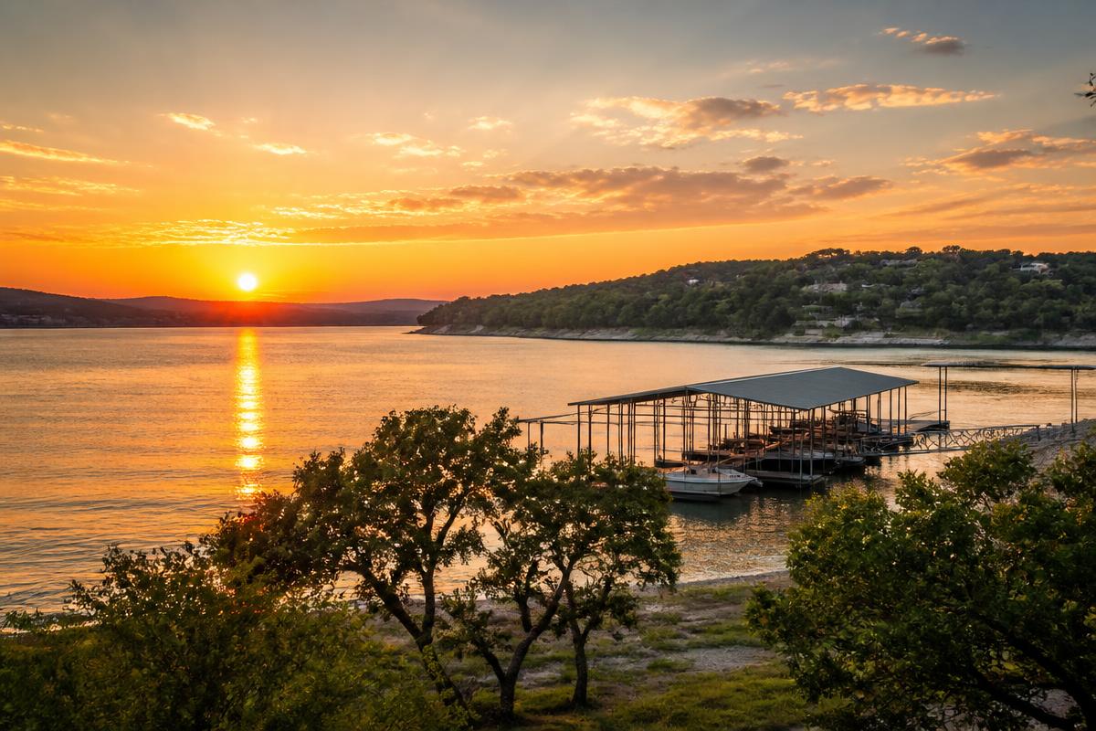 Sunset over Lake Travis in the Texas Hill Country with a boat dock and live oaks